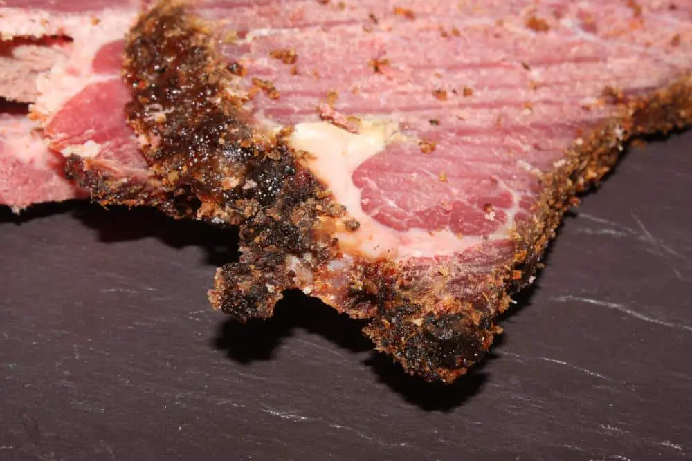 A delicious piece of pastrami with seasoning on its edges